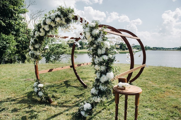 緑の芝生の路上での結婚式。式典のための新鮮な花のアーチで飾る。