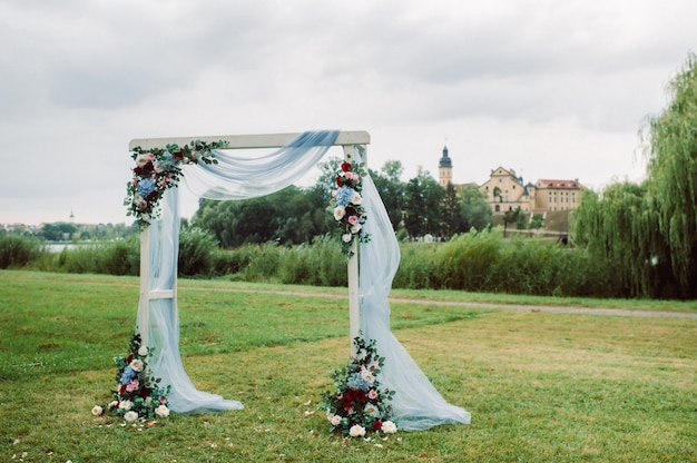 Matrimonio in strada sul prato verde. decorazioni con archi di fiori freschi per la cerimonia.