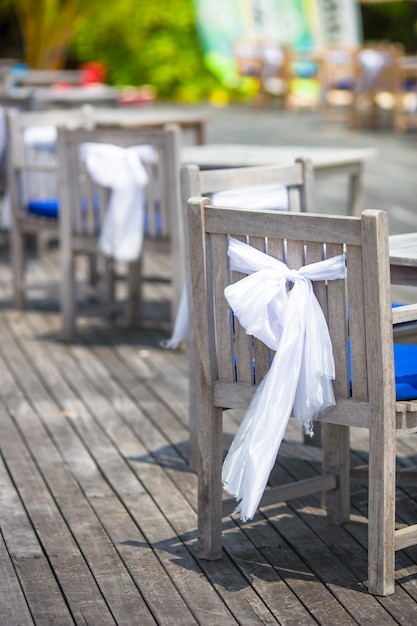 Wedding chairs decorated with white bows at outdoor cafe