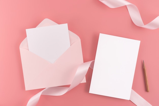 A wedding concept. Wedding Invitation card on pink background with ribbon and decoration. 