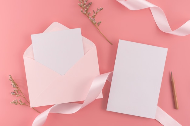 결혼식 개념. 리본 및 장식 분홍색 배경에 결혼식 초대 카드.