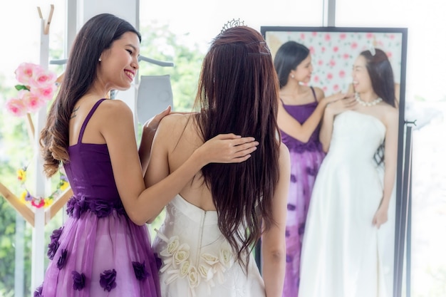 Wedding concept; Woman assisting bride getting dressed in wedding gown.