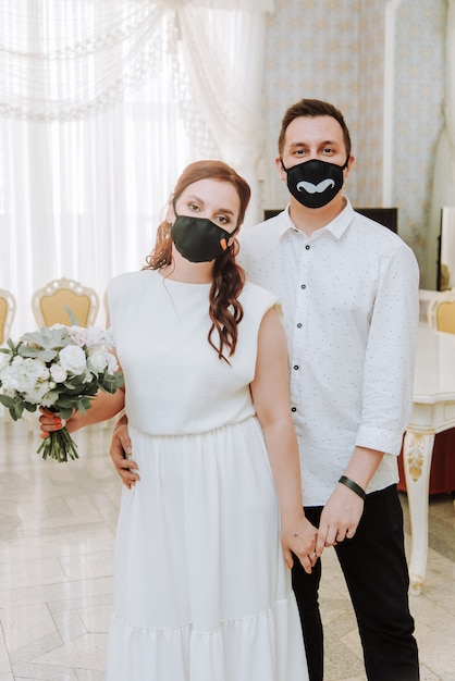 Wedding during the coronavirus epidemic. Bride and groom in protective medical masks. Marrieds and Covid-19 pandemic.