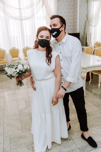 Wedding during the coronavirus epidemic. Bride and groom in protective medical masks.