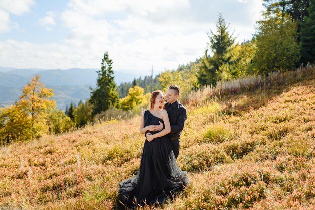 秋の山々を背景に結婚式のカップル