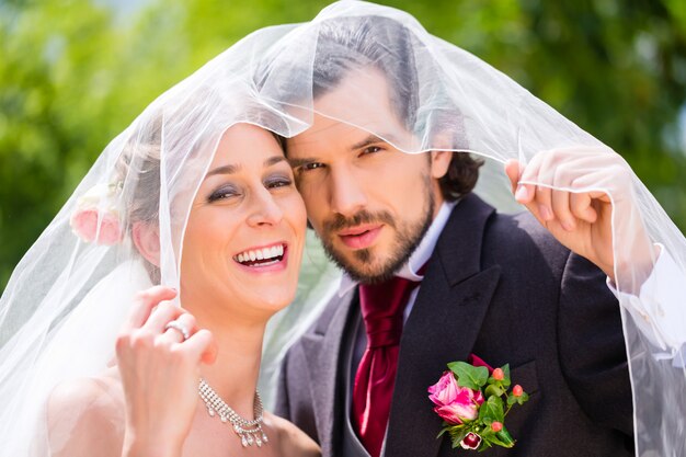 Wedding couple bride and groom hiding under veil