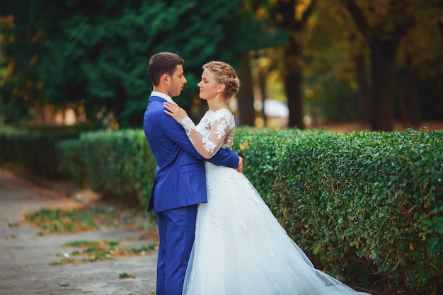 Sposa delle coppie di nozze in vestito da sposa bianco e sposo che camminano nel legno