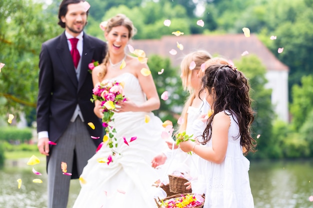 Wedding couple and bridesmaid showering flowers