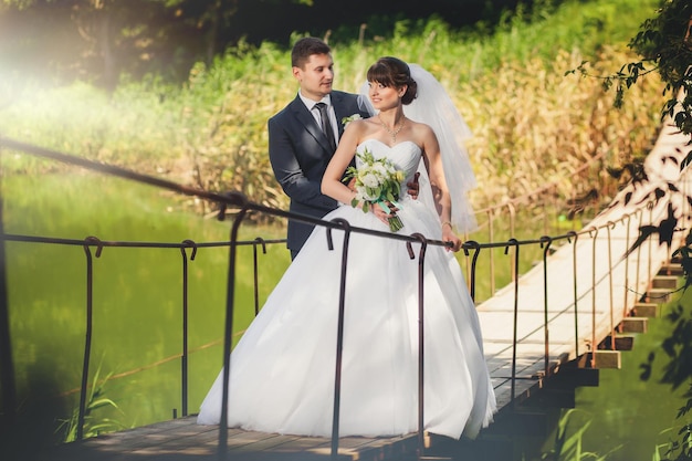 Wedding couple on the bridge over the river in summer