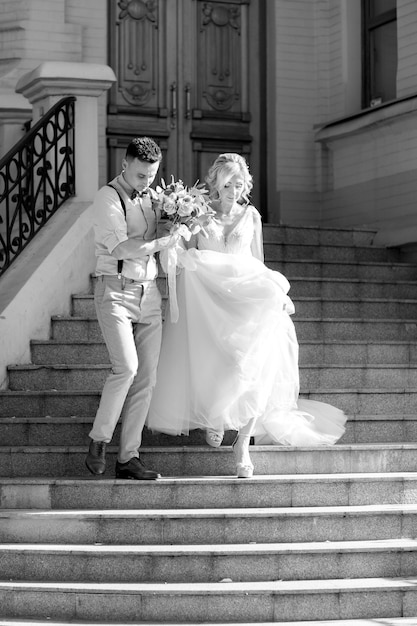 화창한 여름 날에 도시에서 결혼식 한 쌍입니다. 신랑 신부가 계단을 내려갑니다. 검정색과 흰색