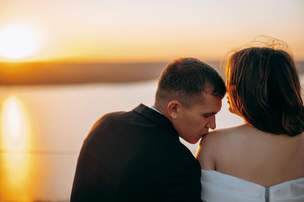 Wedding couple in the evening Man kissing his wife at the shoulder Peaceful romantic moment Love concept