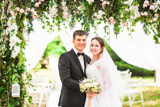 Wedding couple under the flower arch at the wedding ceremony