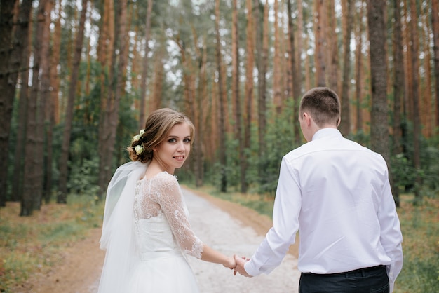 森の中の結婚式のカップル。美しい散歩に新郎新婦。
