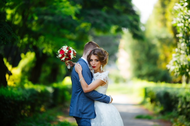 Wedding couple, happy newlyweds and husband hugging in green park.