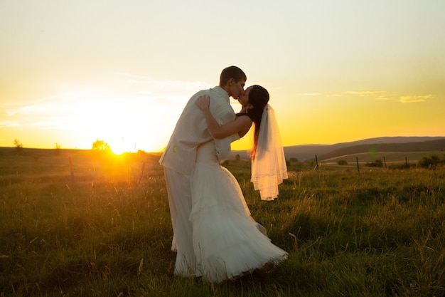 結婚式のカップルは日没で踊っています