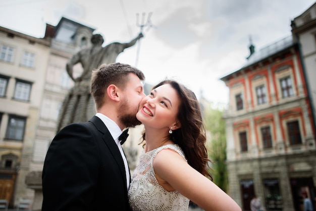 Matrimonio coppia baci prima della statua nel centro della città