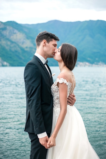 結婚式のカップルが湖と山の背景にキス