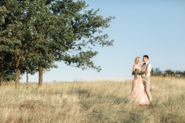 夏の日の自然の結婚式のカップル。結婚式で抱き締める新郎新婦。