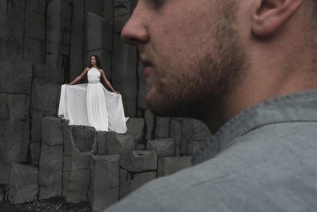 Wedding couple under a rock of basalt stones. the bride and
groom on a black vik beach