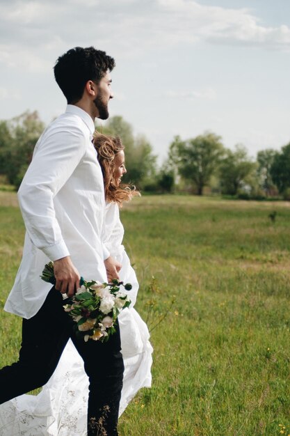 草原で走る結婚式のカップル