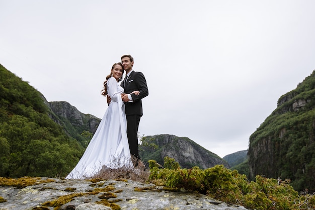 A wedding couple standing on a rock covered with moss