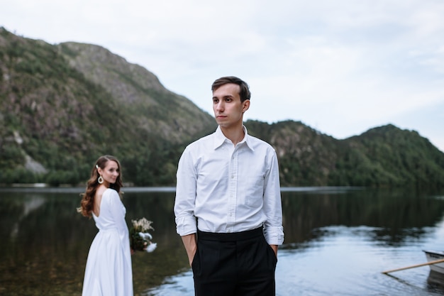 湖の岸に立っている結婚式のカップル