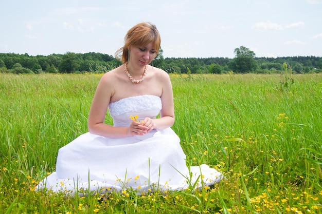 フィールドの真ん中に結婚式の日の美しさの自然の概念彼女は自分の周りを回転している白い花嫁のドレスを着ている素晴らしい女性があり、スパンコールは太陽の光の中で輝いています