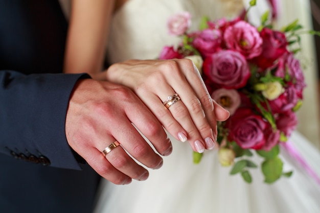 Foto giorno del matrimonio. sposi alla cerimonia di matrimonio. mani della sposa e dello sposo con anelli di nozze d'oro
