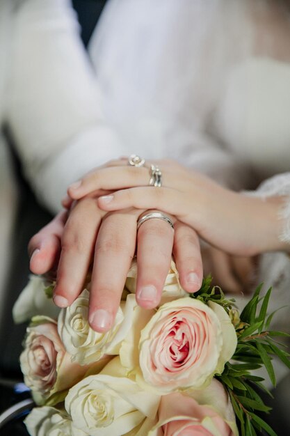 Foto bouquet da sposa di giorno di nozze nelle mani dei dettagli del primo piano degli anelli di nozze della sposa