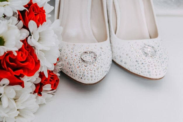 Wedding decor, details of the morning of the bride. White shoes in rhinestones and wedding rings