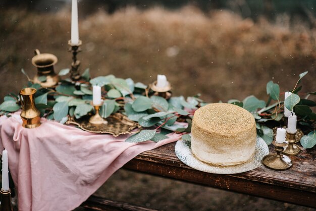 Wedding decor with a golden cake on a wooden bench against a waterfall background