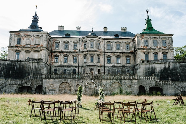 Wedding decor Wooden chairs road in the backyard banquet area Arch for wedding ceremony a is decorated with flowers and greens greenery Against the background of the old castle