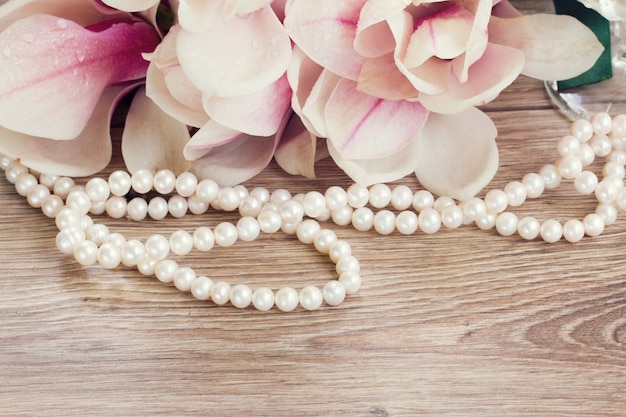 Wedding decorations  - magnolia flowers with strand of pearls on wooden table