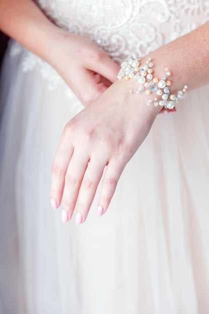 Dettagli e accessori per il matrimonio. preparazione della sposa, sposa che indossa gioielli, focus sul braccialetto di perle. la donna ha la preparazione finale per la cerimonia di nozze. momenti del giorno del matrimonio.