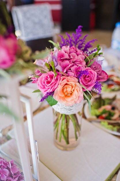 Cena di nozze nel ristorante, tavoli decorati con vasi di rose.