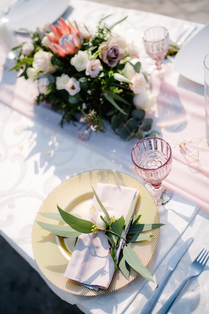 Piatto d'oro per il ricevimento del tavolo da pranzo di nozze con tovagliolo di stoffa rosa e foglie di ulivo lampone vecchio