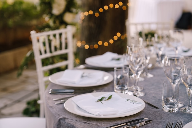 結婚披露宴の白い丸いプレートと灰色のテーブルクロスホワイトのラウンドテーブル