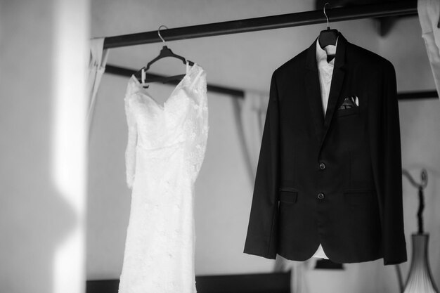 結婚式のドレスとスーツがラックにぶら下がっている