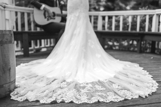 Foto il vestito da sposa, il treno e lo sposo che suona la chitarra.