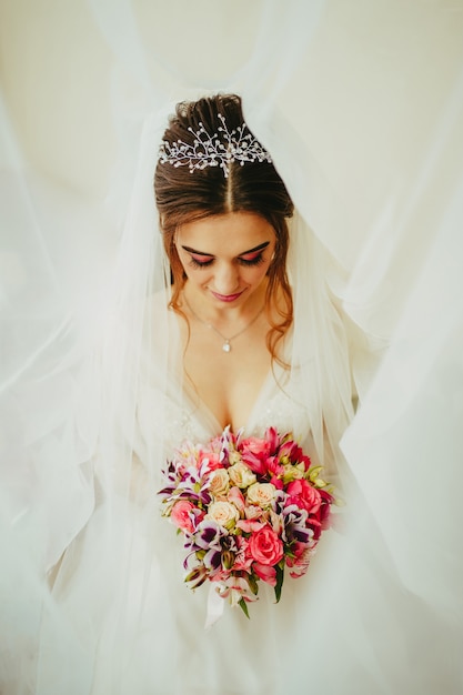 彼女の手に花束を持ったウェディングドレスで。白い背景の上の花束と花嫁