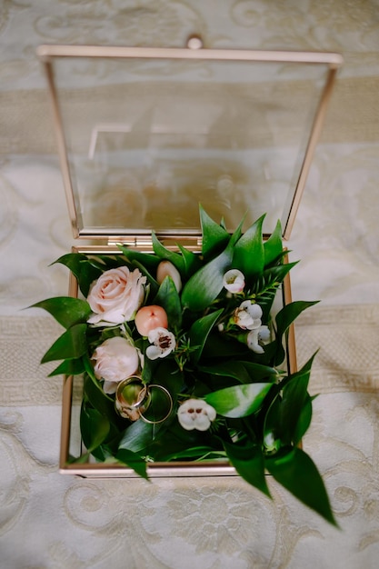 明るい背景に、ガラスの箱に入った花の婚約指輪。結婚式
