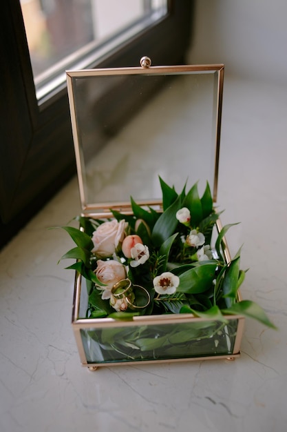 Wedding engagement rings on flowers in a glass box, on a light
background. wedding ceremony