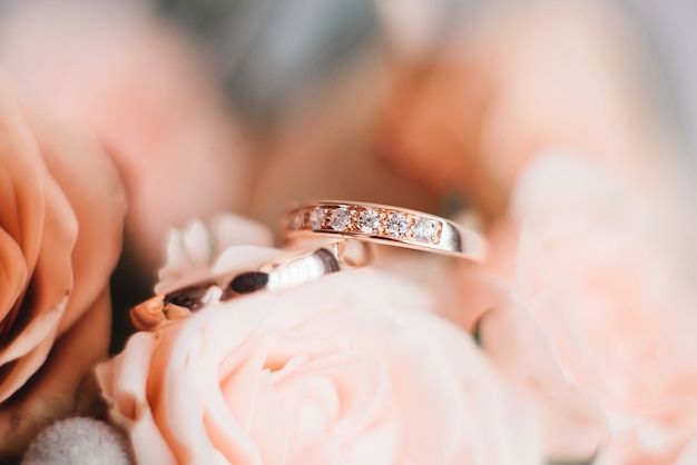 Photo wedding engagement rings and flowers wedding bouquet background, selective focus, macro