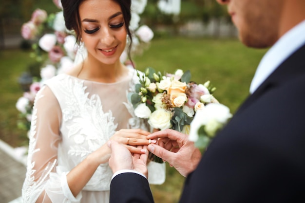 Wedding engagement rings Groom put a ring on finger of his lovely wife Concept wedding details.