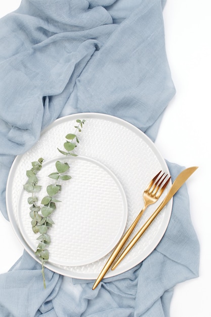 Wedding or festive table setting. Plates and cutlery with gray decorative textile on white background. Beautiful arrangement.