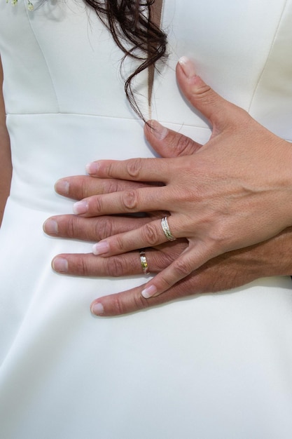 白いドレスの背景に新郎新婦の手に結婚式の指輪