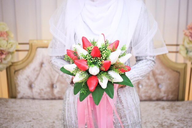 결혼식 날에 그녀의 손으로 빨간 부케를 들고 결혼식 꽃 신부