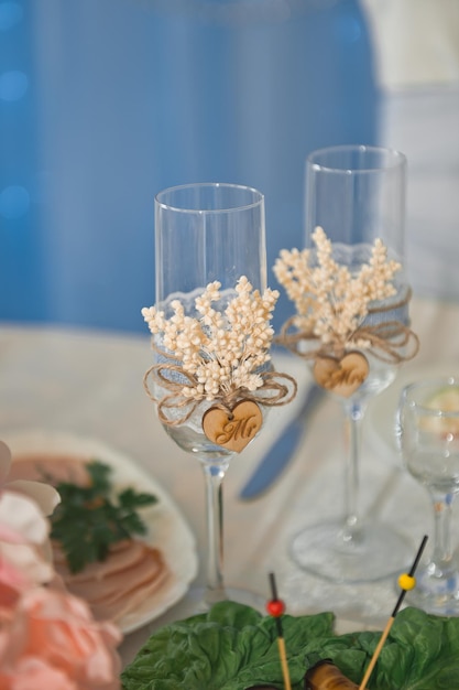 Wedding glasses are beautifully decorated with branches and a wooden