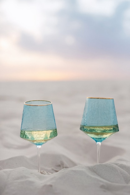 Wedding glasses made of blue glass buried in the sand of the beach