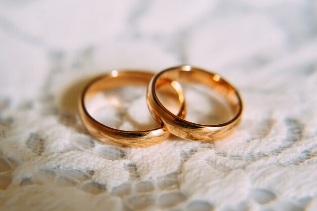 Обручальные золотые кольца на кружевной ткани